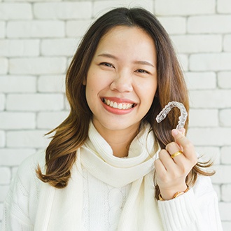 Woman holding up a clear orthodontic alignment tray