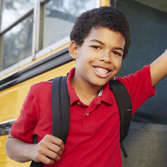 Preteen boy with orthodontic appliance smiling as he gets on a bus