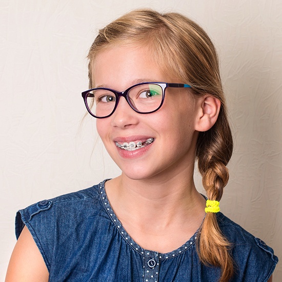 Young woman with braces smiling after dentofacial orthopedic treatment