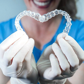 dentist holding two aligners in the shape of a heart 