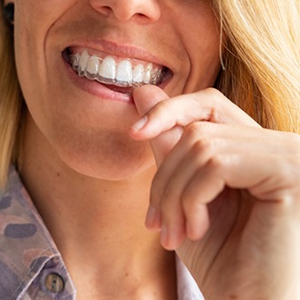 Woman placing Invisalign in Hopkinton in mouth