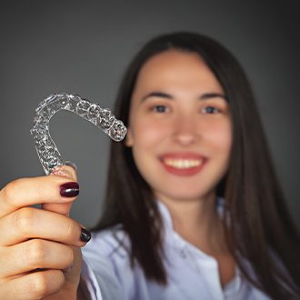 Woman holding up an Invisalign tray