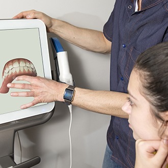 Orthodontist and patient looking at Invisalign smile design on computer screen