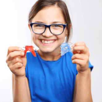 Preteen girl holding up orthodontic appliances