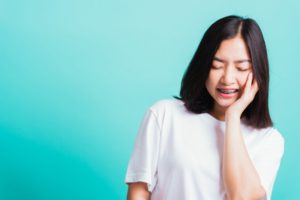 Pained girl with braces and orthodontic emergency on blue background