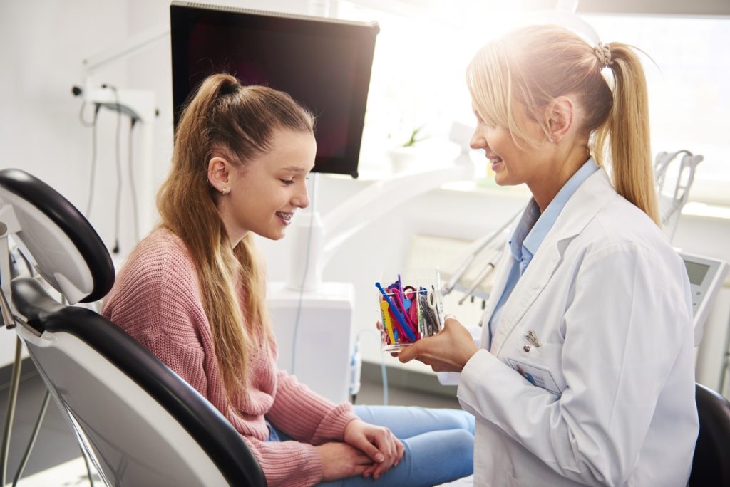 Orthodontist showing patient rubber band colors for braces