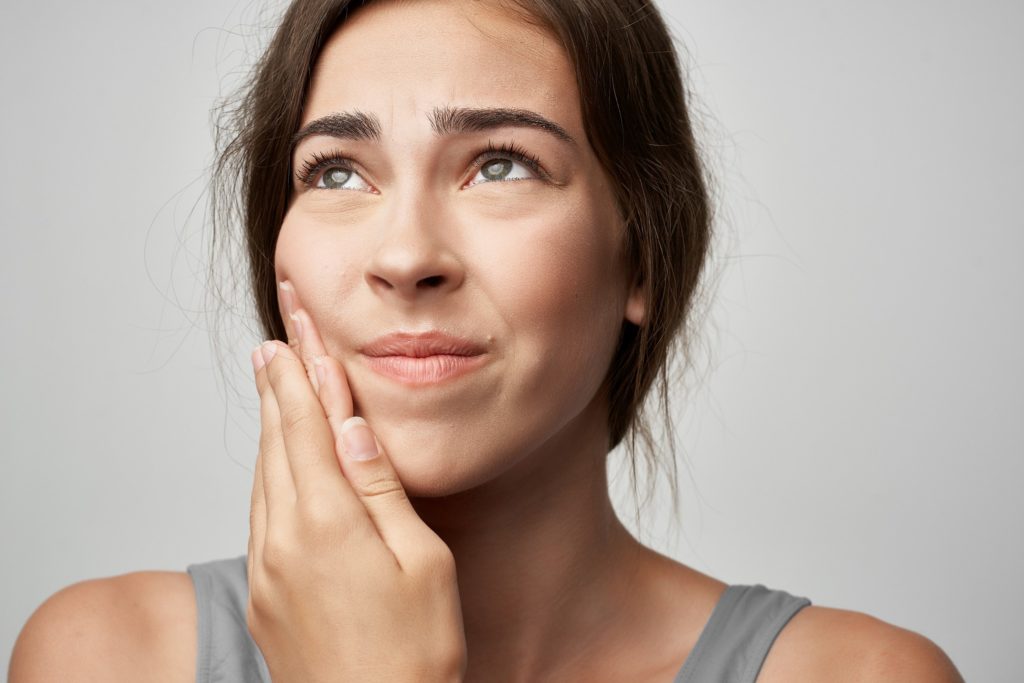 Closeup of woman experiencing a sore mouth from braces