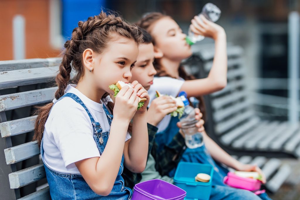 Young girl with braces eating her lunch at school