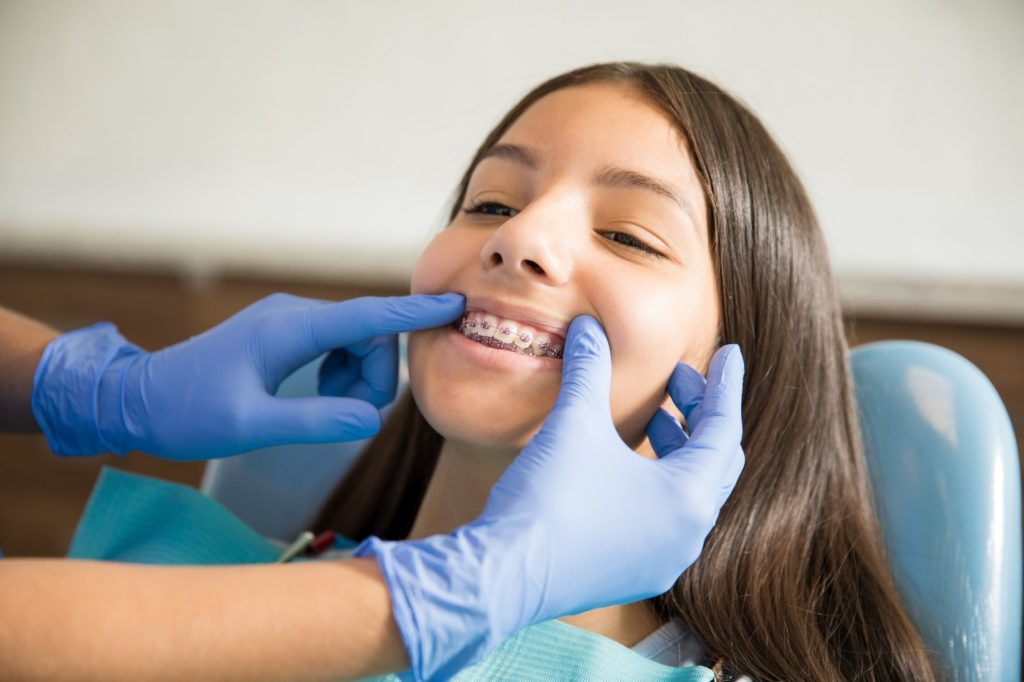 Orthodontist examining patient's braces