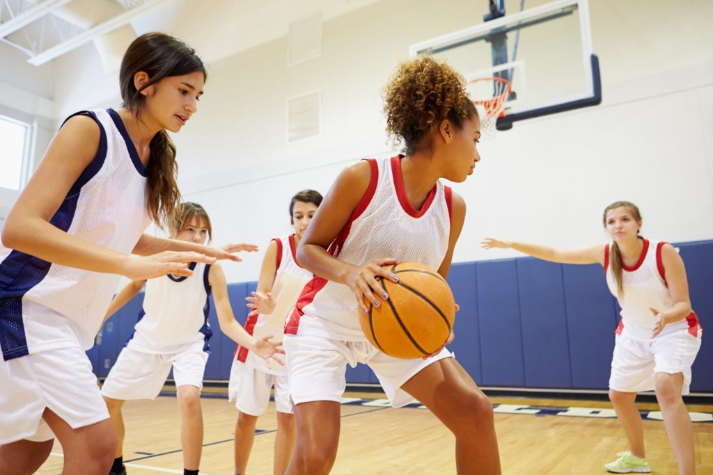 Teen girl playing basketball at school