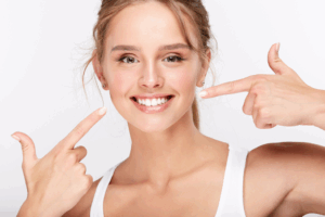 a person smiling and pointing to their teeth